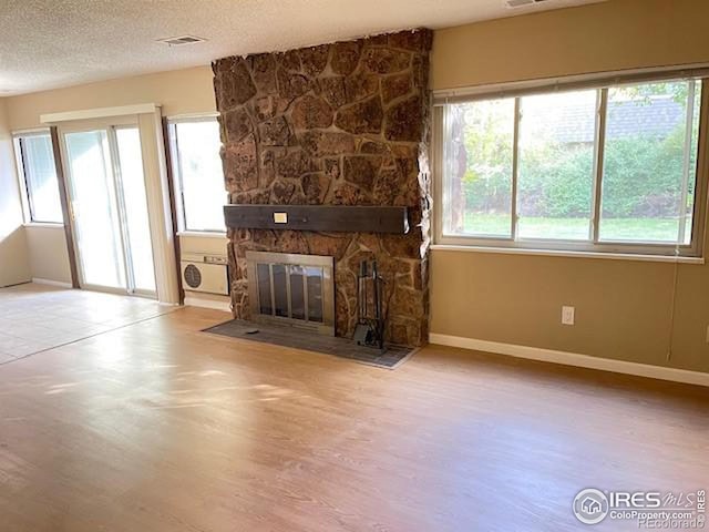 3345 Chisholm Trl Unit 105C, Boulder, CO 80301 - unfurnished living room featuring wood finished floors, healthy amount of natural light, a fireplace, baseboards, and a textured ceiling