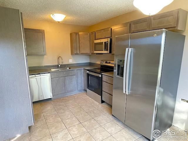 3345 Chisholm Trl Unit 105C, Boulder, CO 80301 - kitchen featuring appliances with stainless steel finishes, a sink, a textured ceiling, light tile patterned floors, and dark countertops