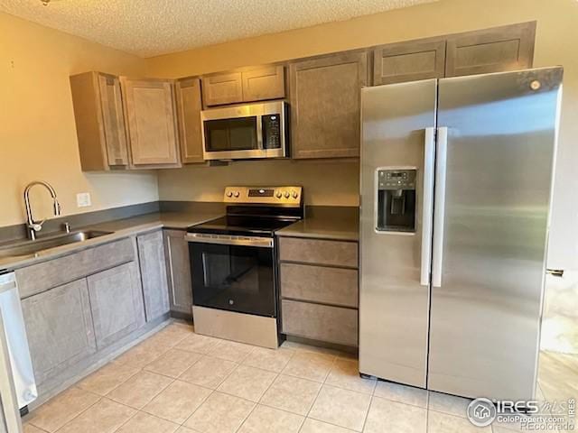 3345 Chisholm Trl Unit 105C, Boulder, CO 80301 - kitchen featuring stainless steel appliances, a sink, a textured ceiling, light tile patterned floors, and dark countertops