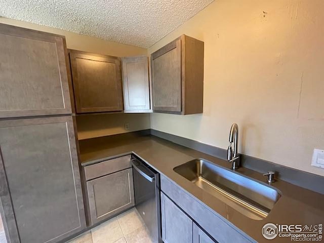 3345 Chisholm Trl Unit 105C, Boulder, CO 80301 - kitchen featuring stainless steel dishwasher, a sink, a textured ceiling, dark countertops, and light tile patterned floors