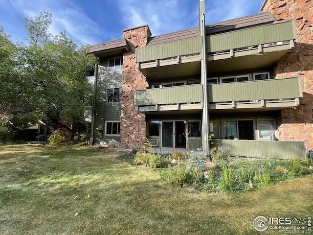 3345 Chisholm Trl Unit 105C, Boulder, CO 80301 - rear view of property featuring a balcony, a yard, a chimney, and stone siding