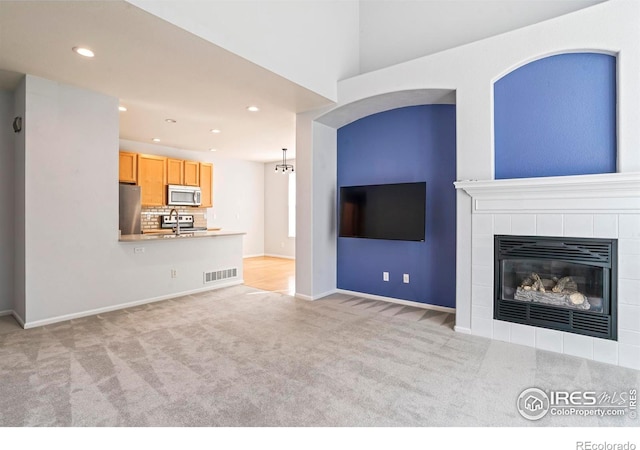 unfurnished living room with light carpet, sink, and a fireplace