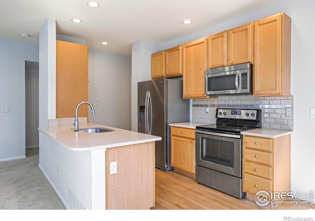 kitchen with appliances with stainless steel finishes, sink, backsplash, kitchen peninsula, and light hardwood / wood-style floors