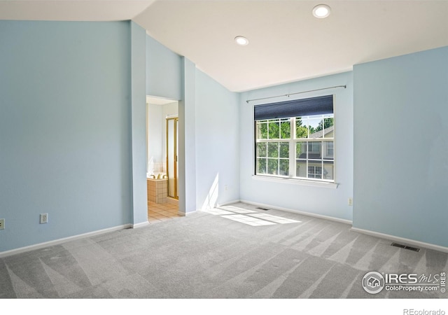 unfurnished room featuring lofted ceiling and light colored carpet