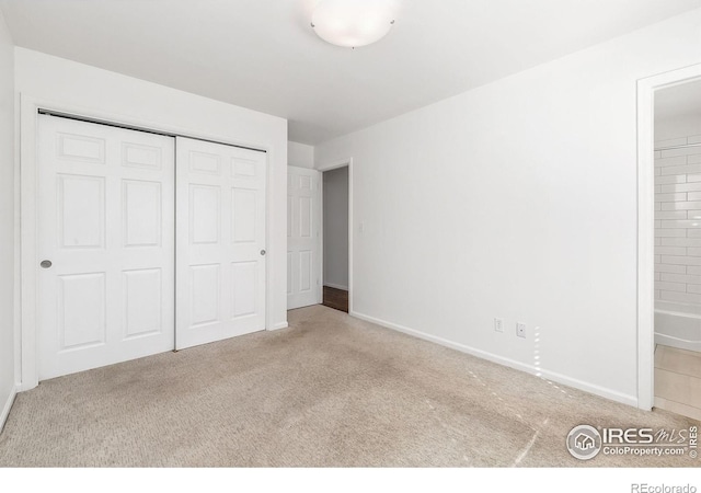 unfurnished bedroom featuring light carpet and a closet