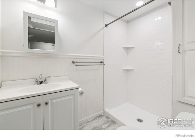 bathroom featuring vanity, a tile shower, and toilet