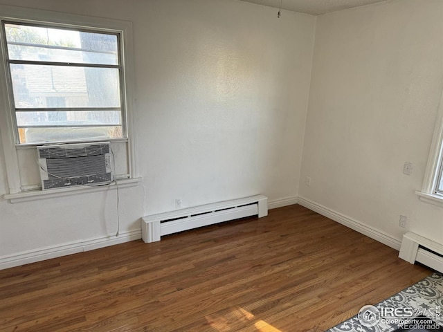 spare room with a baseboard heating unit and dark hardwood / wood-style floors