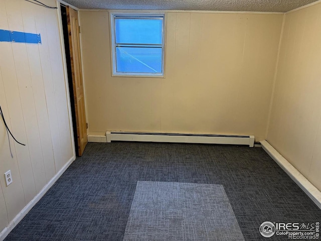 empty room with wood walls, a textured ceiling, and baseboard heating