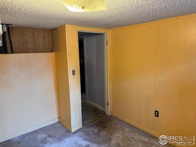 unfurnished room featuring wooden walls and a textured ceiling