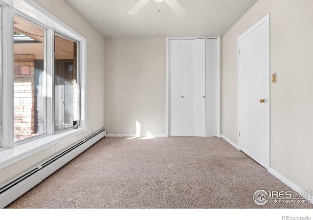 unfurnished bedroom featuring multiple windows, a baseboard heating unit, carpet floors, and a closet