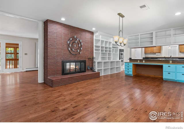 kitchen with an inviting chandelier, hanging light fixtures, dark hardwood / wood-style floors, a fireplace, and a baseboard radiator