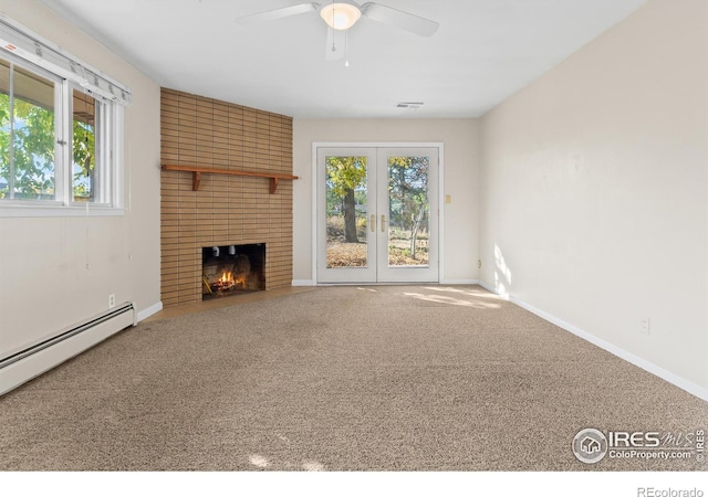 unfurnished living room featuring ceiling fan, a baseboard heating unit, carpet flooring, a brick fireplace, and french doors