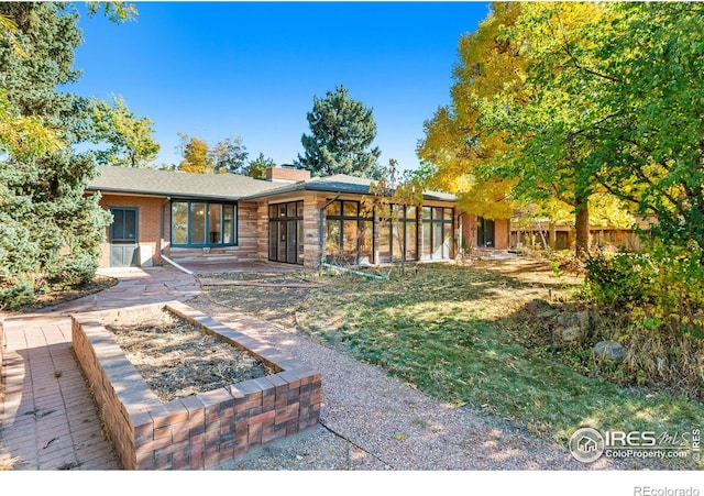 back of house featuring a sunroom and a lawn