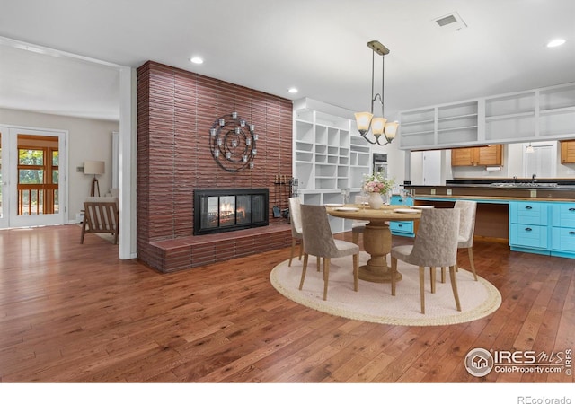 dining space featuring dark hardwood / wood-style flooring, a brick fireplace, and an inviting chandelier