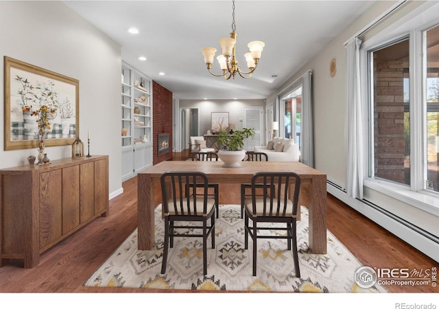 dining room with a notable chandelier, wood-type flooring, and a baseboard heating unit