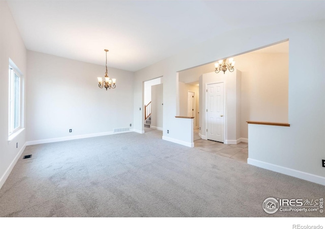 spare room featuring an inviting chandelier and light colored carpet