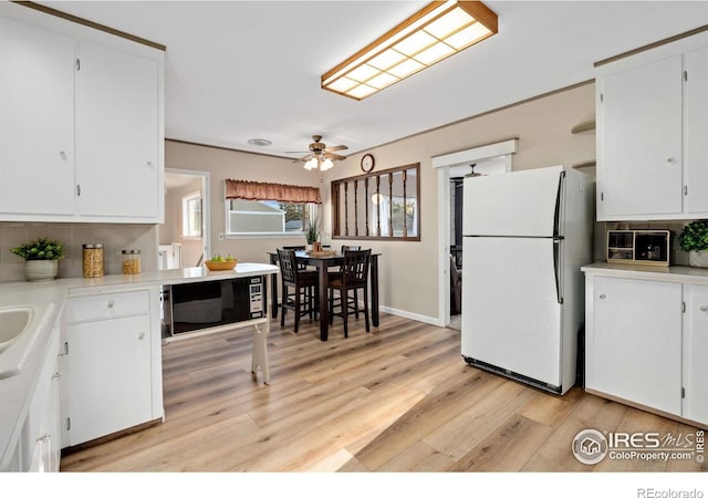 kitchen with ceiling fan, backsplash, white cabinetry, light wood-type flooring, and white refrigerator