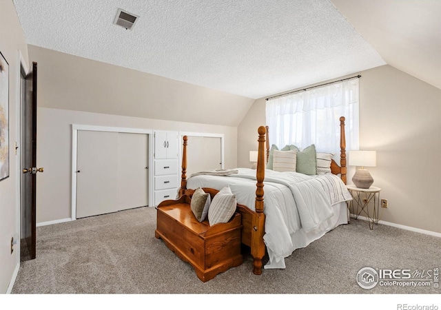 bedroom with vaulted ceiling, light carpet, and a textured ceiling