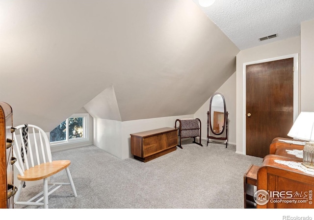 carpeted bedroom featuring a closet, a textured ceiling, and vaulted ceiling