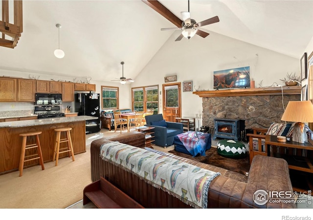 living room with a wood stove, light carpet, high vaulted ceiling, and ceiling fan