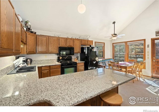 kitchen with black appliances, sink, backsplash, kitchen peninsula, and pendant lighting