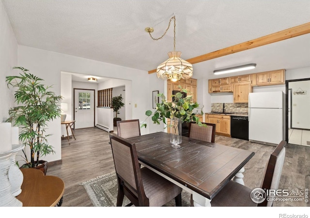 dining area with a baseboard heating unit, hardwood / wood-style flooring, sink, and a textured ceiling