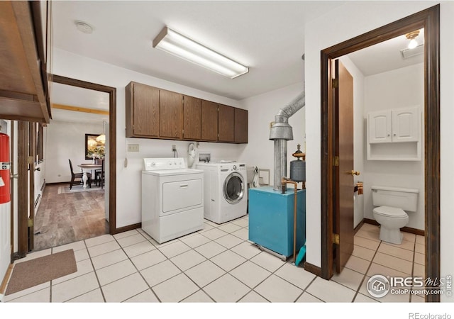 laundry area with cabinets, washing machine and dryer, and light tile patterned floors