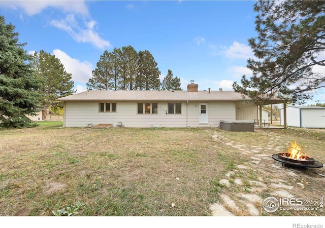 rear view of property featuring a yard and a fire pit