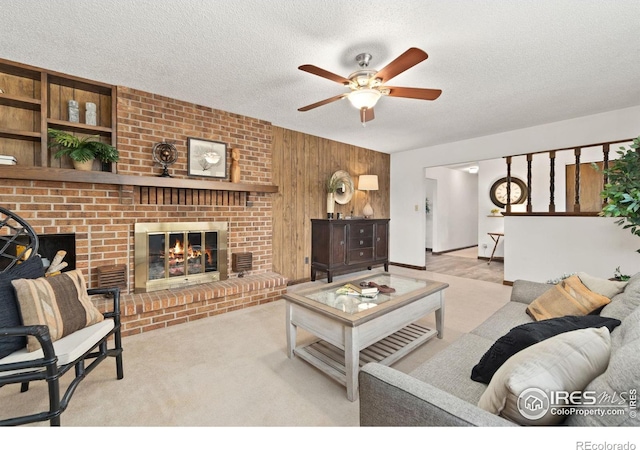 living area with a textured ceiling, ceiling fan, carpet floors, wood walls, and a fireplace