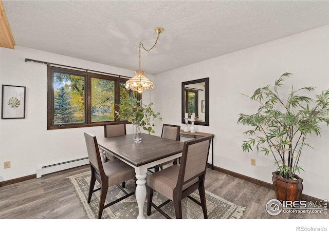 dining space featuring a baseboard radiator, a textured ceiling, baseboards, and wood finished floors