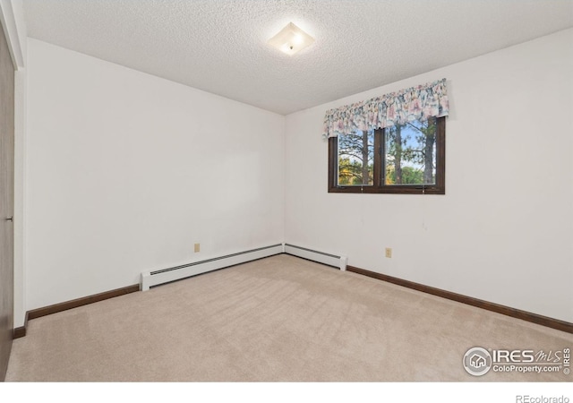 carpeted spare room with a textured ceiling, baseboard heating, and baseboards