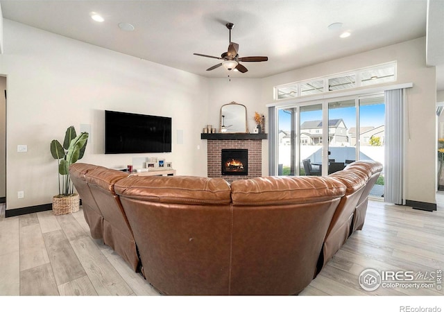 living room with ceiling fan, a fireplace, and light wood-type flooring