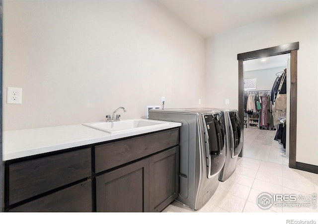 washroom featuring sink, light tile patterned floors, washing machine and dryer, and cabinets