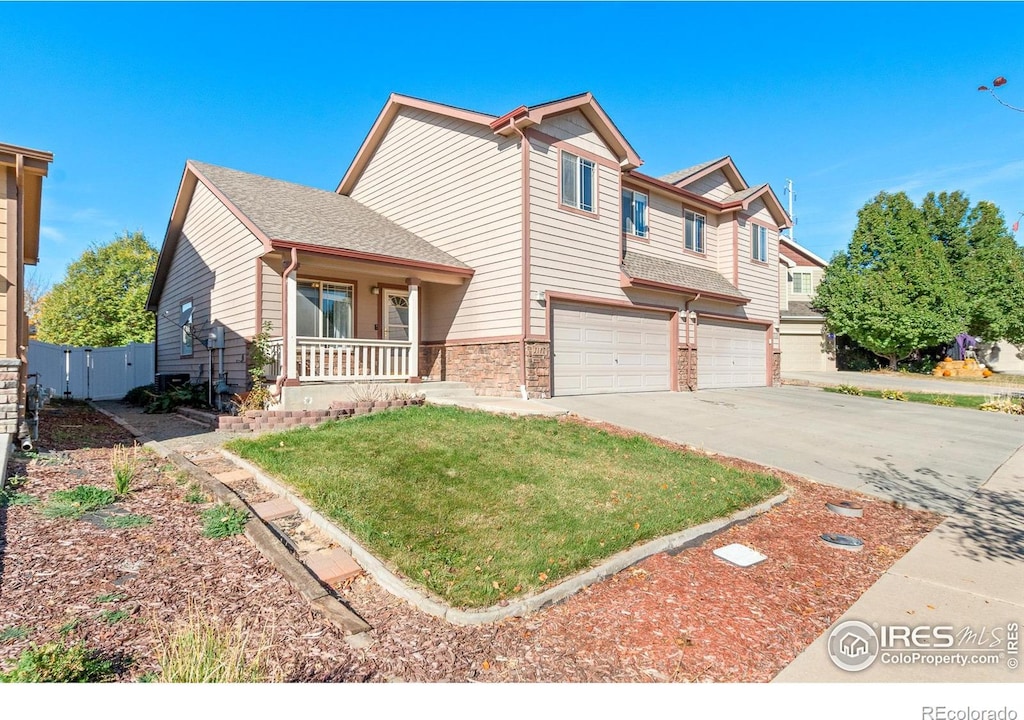 view of front of house featuring covered porch, a garage, and a front yard