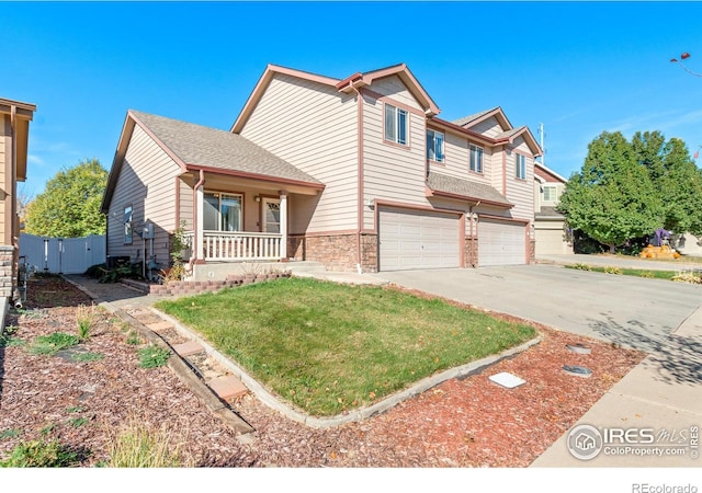 view of front of house featuring covered porch, a garage, and a front yard