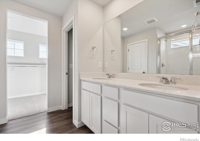 bathroom with wood-type flooring, vanity, and a shower with shower door