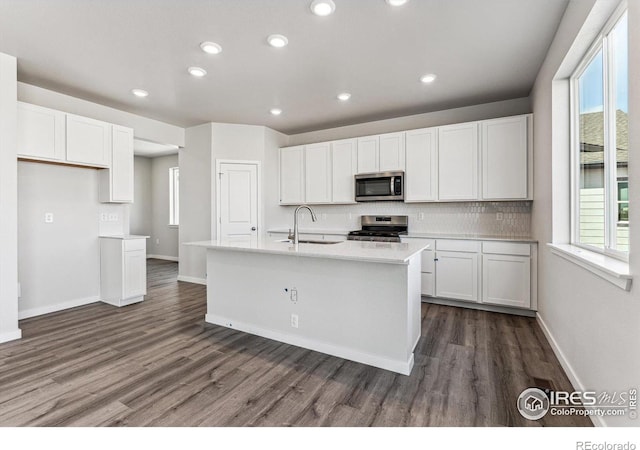 kitchen featuring appliances with stainless steel finishes, white cabinets, sink, and a center island with sink