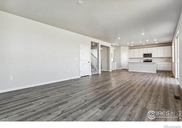 unfurnished living room with hardwood / wood-style flooring and sink