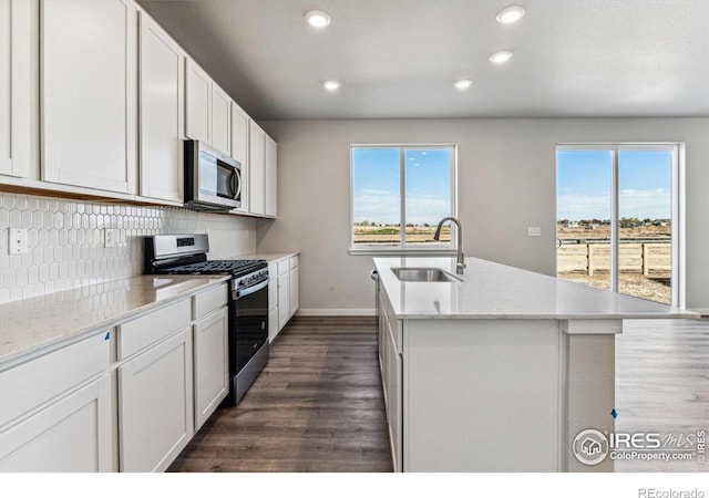 kitchen featuring dark hardwood / wood-style floors, an island with sink, sink, white cabinets, and appliances with stainless steel finishes