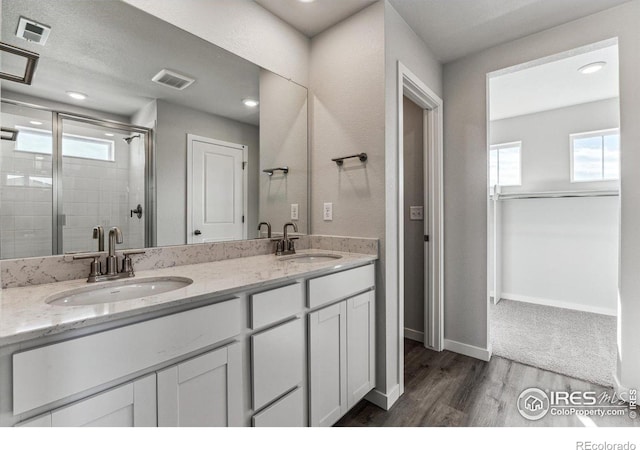 bathroom with vanity, hardwood / wood-style flooring, a wealth of natural light, and a shower with door