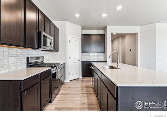 kitchen with tasteful backsplash, sink, light wood-type flooring, stainless steel appliances, and dark brown cabinetry