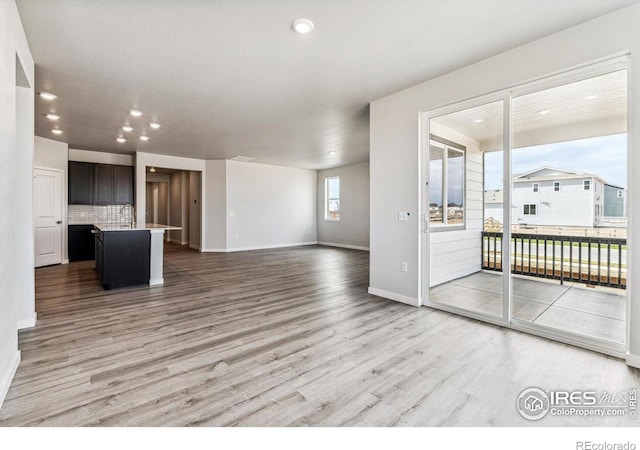 unfurnished living room with hardwood / wood-style floors and sink