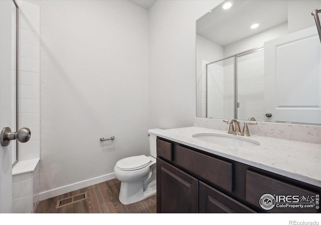 bathroom featuring a shower with door, vanity, wood-type flooring, and toilet