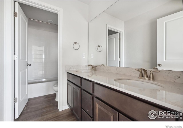 full bathroom with vanity, toilet, wood-type flooring, and tiled shower / bath combo