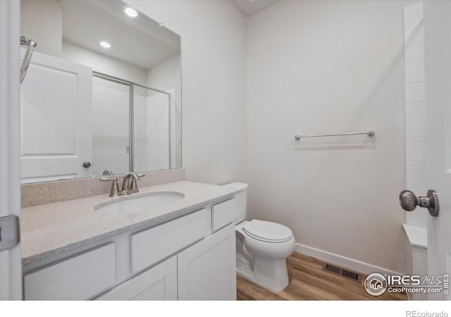 bathroom featuring toilet, vanity, wood-type flooring, and walk in shower