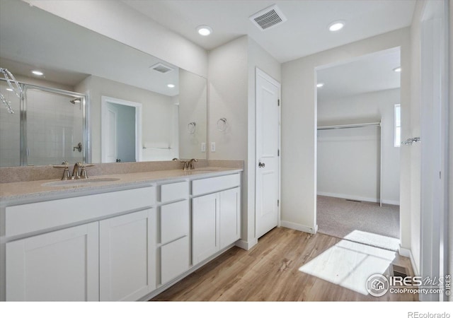 bathroom with hardwood / wood-style floors, vanity, and a shower with door