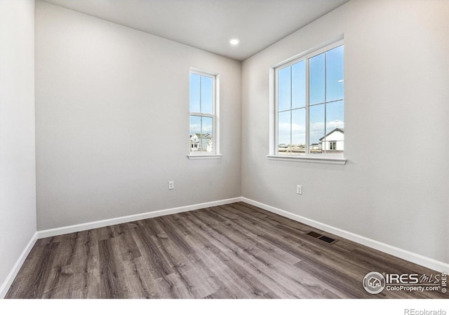 spare room with baseboards, recessed lighting, wood finished floors, and visible vents