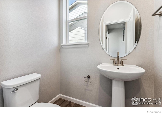 bathroom featuring baseboards, wood finished floors, and toilet
