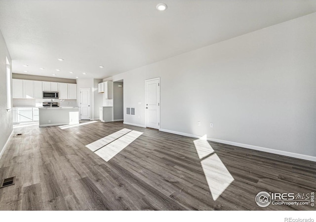 unfurnished living room with recessed lighting, baseboards, visible vents, and dark wood-type flooring