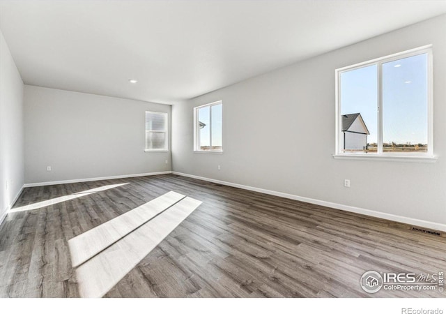 empty room featuring recessed lighting, baseboards, visible vents, and wood finished floors